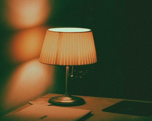 A warm desk lamp illuminating a notebook during evening hours